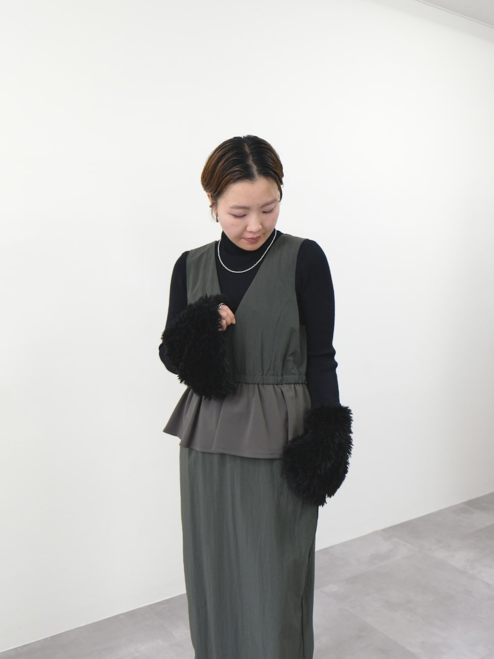 ブラック系のニット/セーター、グリーン系のワンピースを着用したレディースの秋コーディネートの2枚目の写真