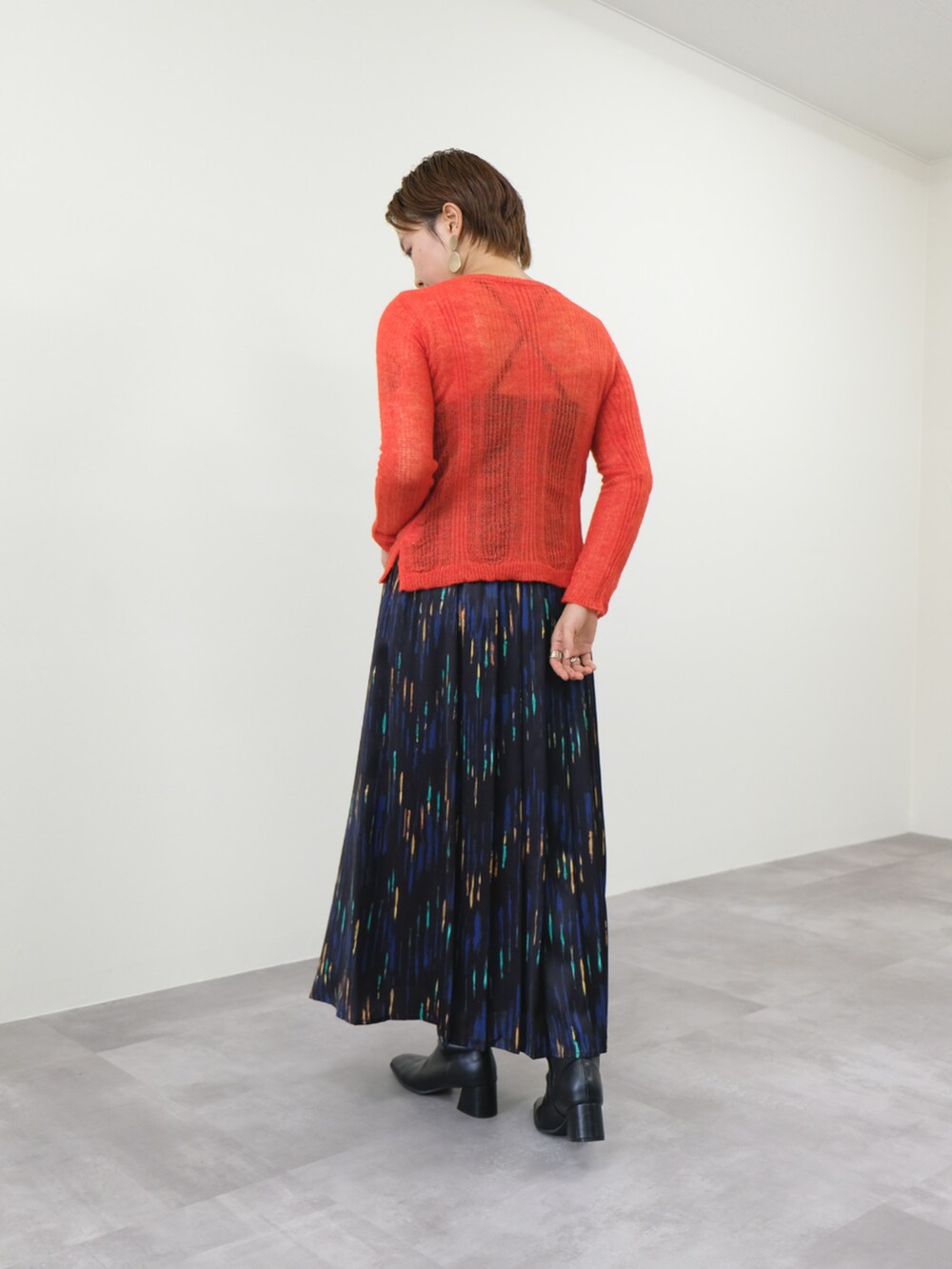 オレンジ系のニット/セーター、ブラック系のスカートを着用したレディースの秋コーディネートの2枚目の写真