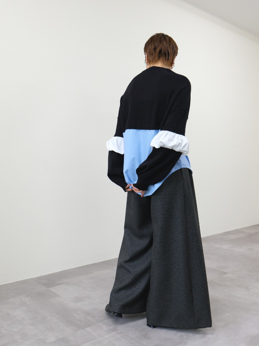 ブラック系のニット/セーター、グレー系のスラックスを着用したレディースの秋コーディネートの2枚目の写真