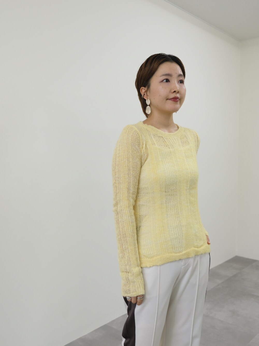 イエロー系のニット/セーター、ホワイト系のその他パンツを着用したレディースの秋コーディネートの2枚目の写真