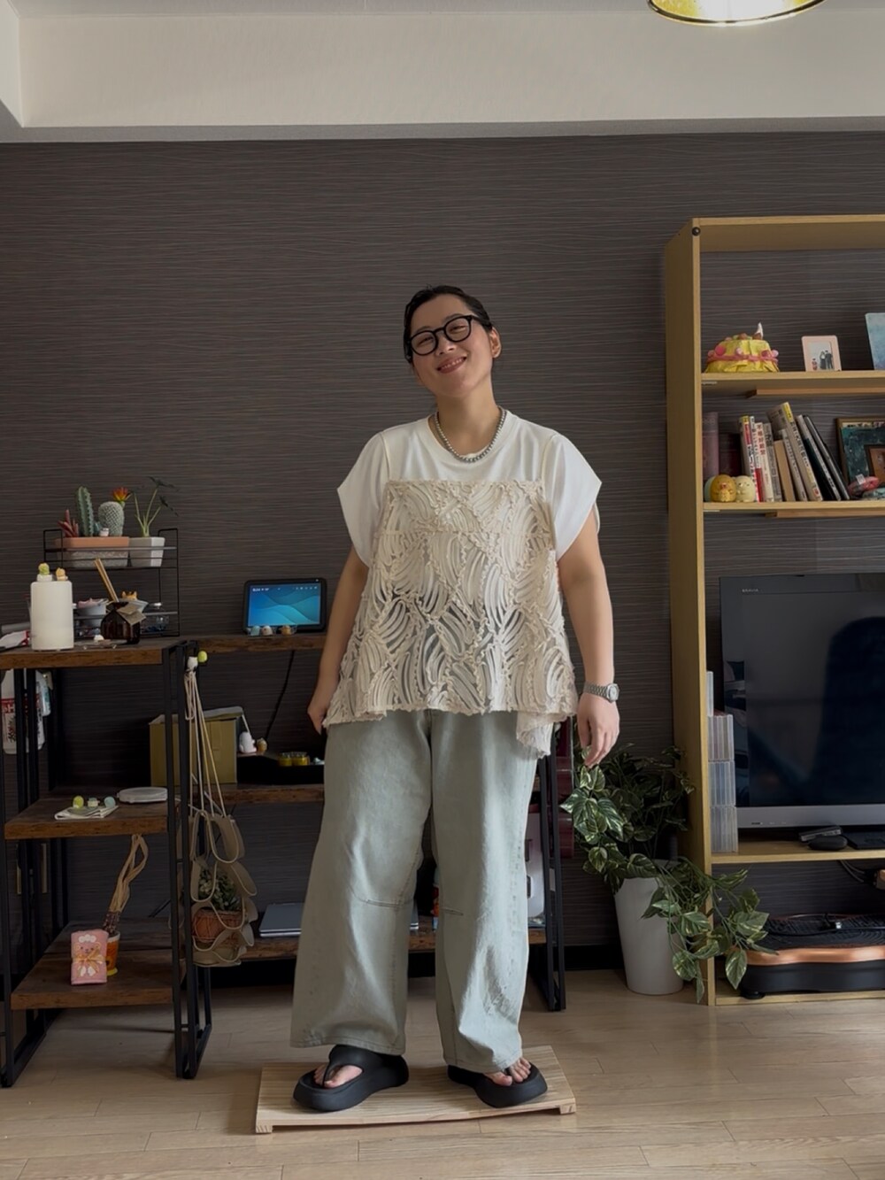 ベージュ系のキャミソール、ブルー系のデニムパンツ、ブラック系のサンダルを着用したレディースの夏コーディネートの2枚目の写真