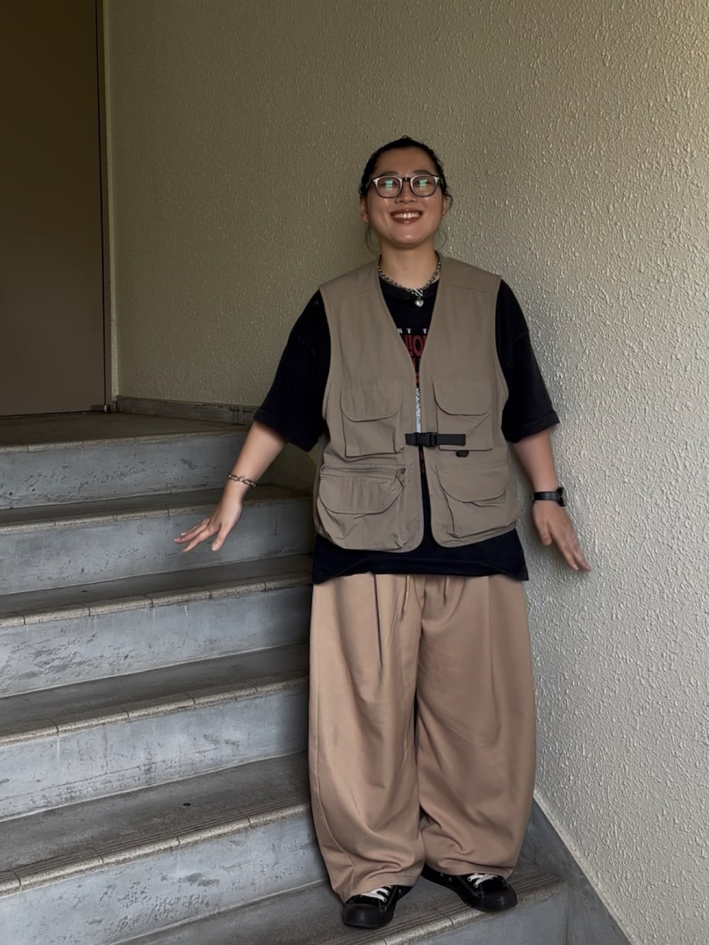 ベージュ系のパンツ、ブラック系のスニーカー、ブラック系のTシャツ/カットソーを着用したレディースの夏コーディネートの2枚目の写真