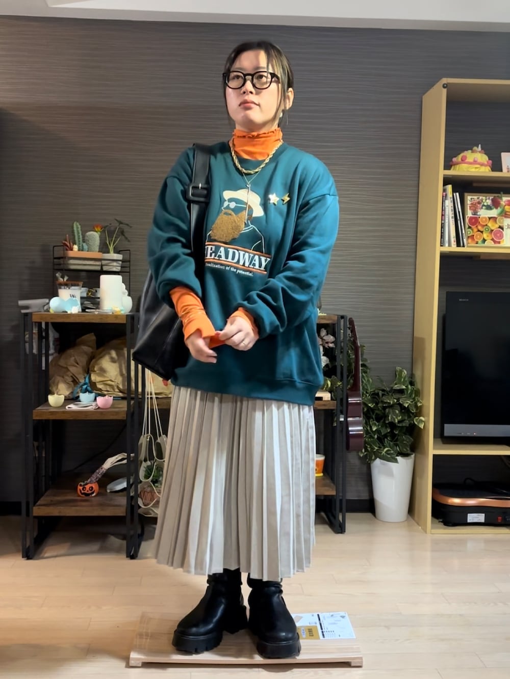 ベージュ系のスカート、ブラック系のブーツ、グリーン系のスウェットを着用したレディースの冬コーディネートの2枚目の写真