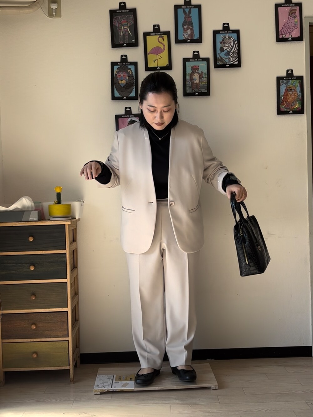 ベージュ系のスーツジャケット、ベージュ系のスーツパンツ、ブラック系のバッグを着用したレディースの冬コーディネートの2枚目の写真