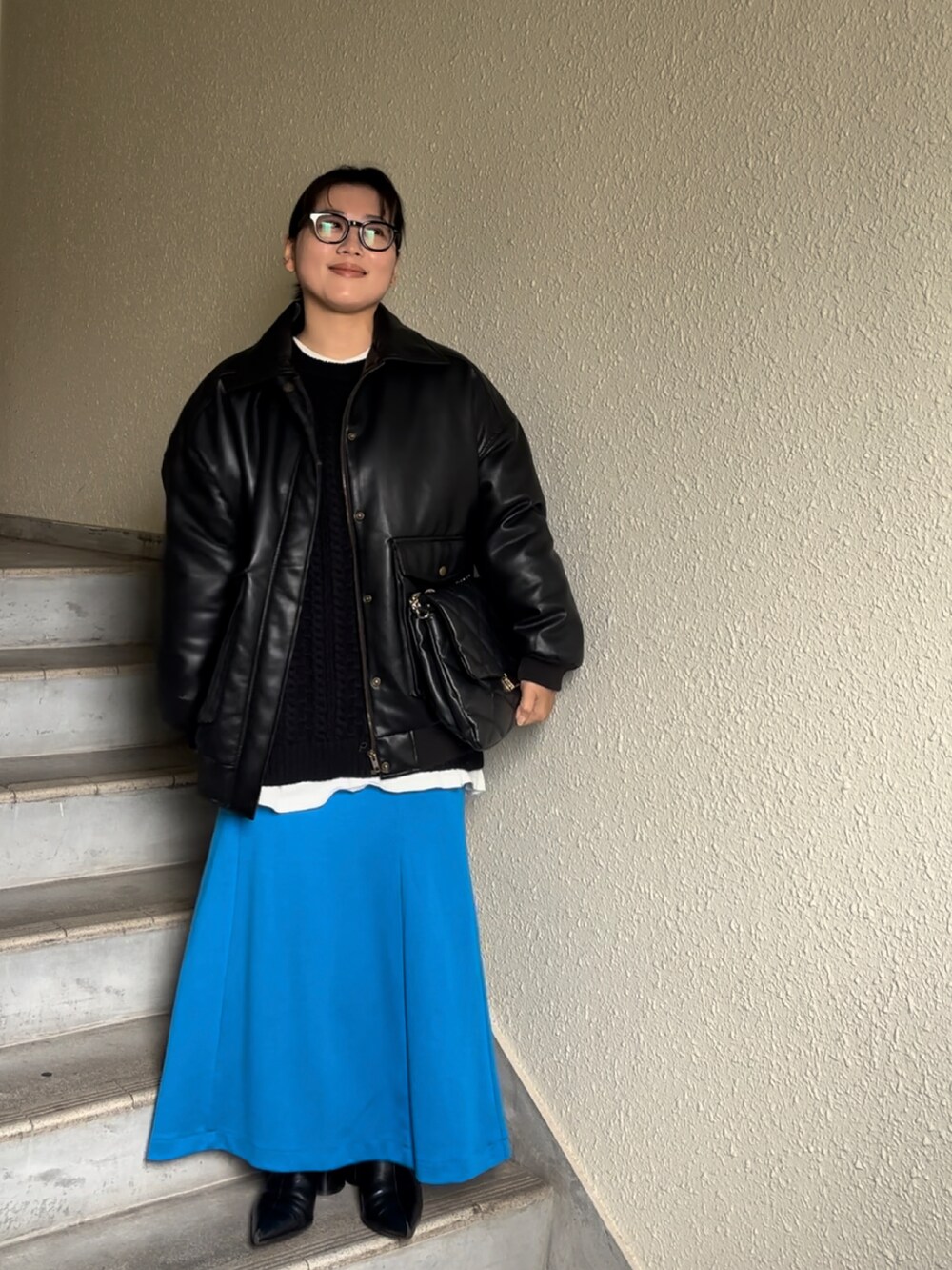 ブルー系のスカート、ブラック系のブーツ、ブラック系のブルゾンを着用したレディースの冬コーディネートの3枚目の写真