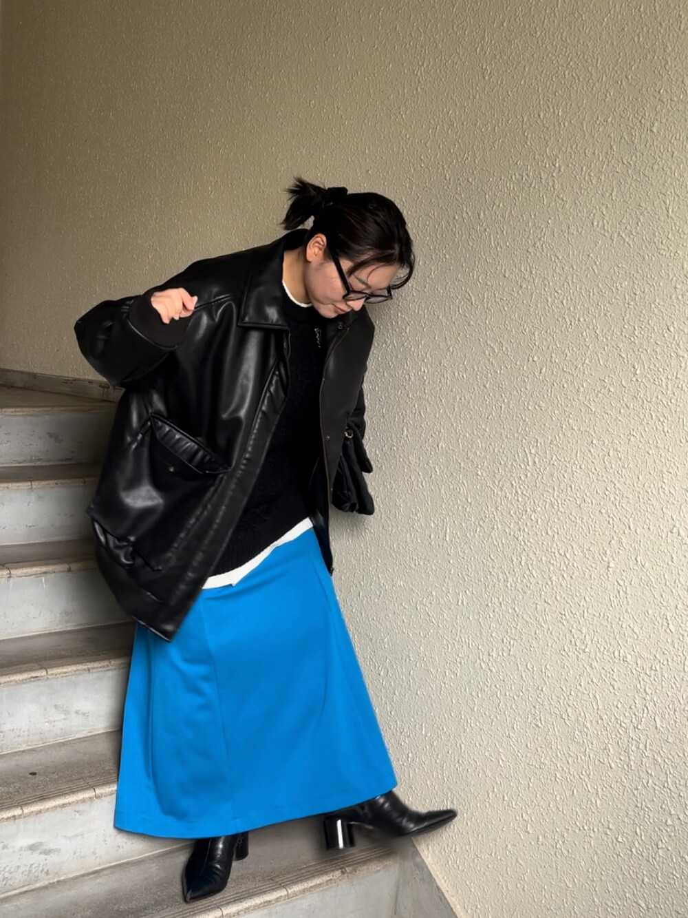 ブルー系のスカート、ブラック系のブーツ、ブラック系のブルゾンを着用したレディースの冬コーディネートの4枚目の写真