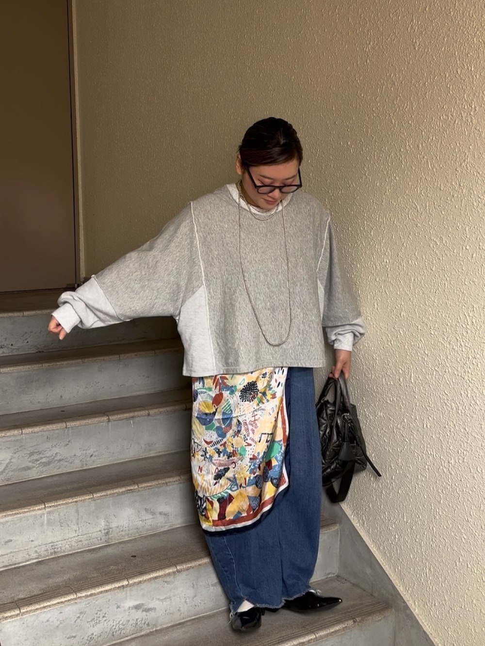 グレー系のスウェット、ブルー系のデニムパンツ、ブラック系のパンプスを着用したレディースの春コーディネートの2枚目の写真