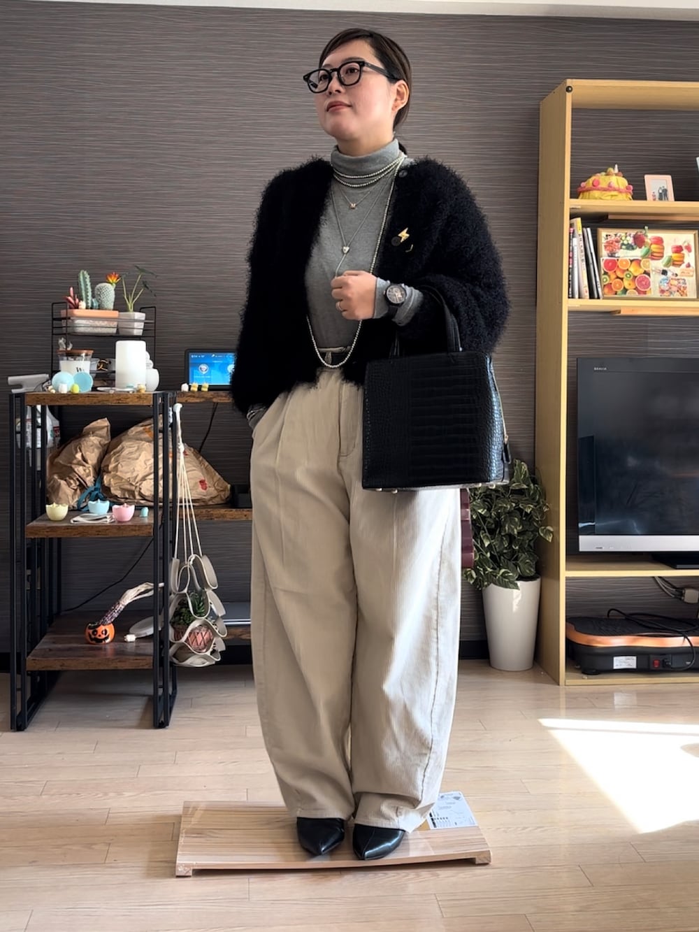 ブラック系のバッグ、ホワイト系のパンツ、ブラック系のカーディガン/ボレロを着用したレディースの冬コーディネートの2枚目の写真