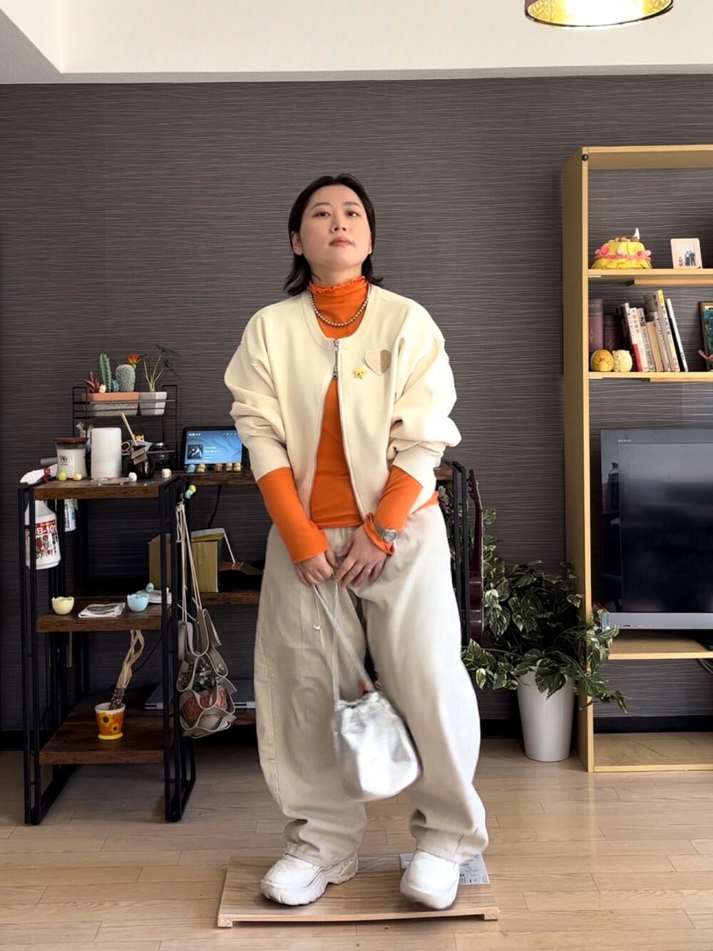 ホワイト系のパンツ、ホワイト系のカーディガン/ボレロ、オレンジ系のTシャツ/カットソーを着用したレディースの春コーディネートの2枚目の写真