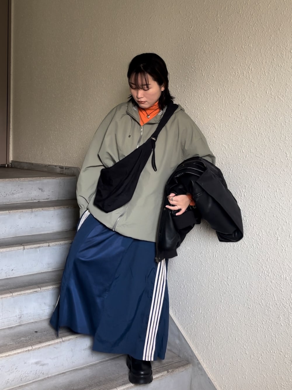 ブラック系のブーツ、ブルー系のスカート、ブラック系のショルダーバッグを着用したレディースの冬コーディネートの2枚目の写真