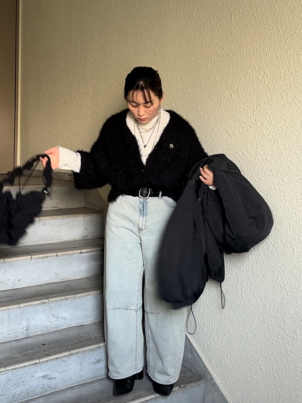 ブラック系のブーツ、ブルー系のデニムパンツ、ブラック系のショルダーバッグを着用したレディースの冬コーディネートの2枚目の写真