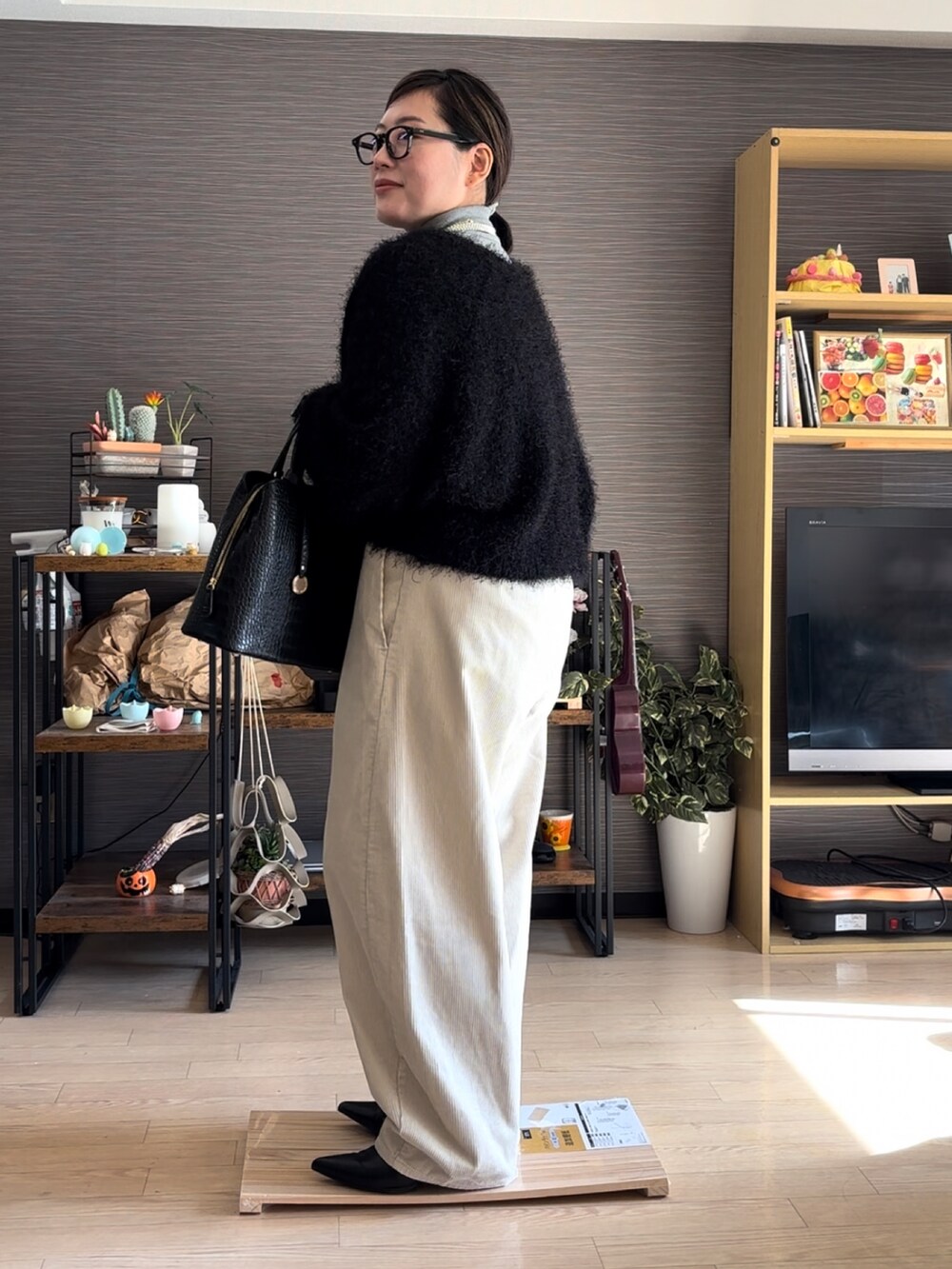 ブラック系のバッグ、ホワイト系のパンツ、ブラック系のカーディガン/ボレロを着用したレディースの冬コーディネートの3枚目の写真