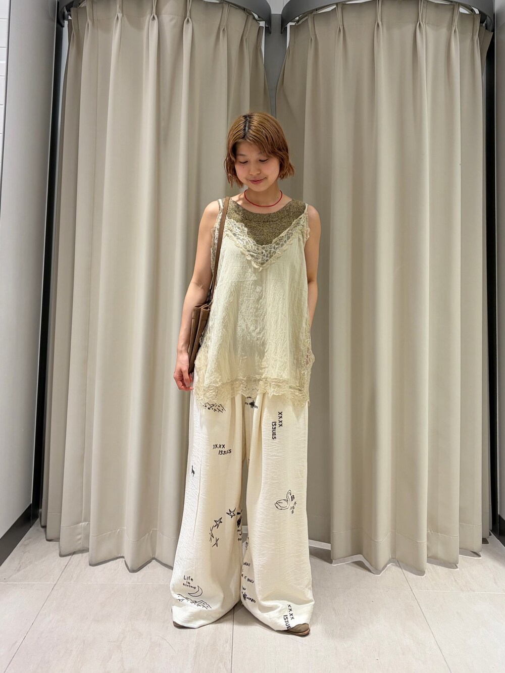 ベージュ系のキャミソール、ホワイト系のその他パンツ、イエロー系のショルダーバッグを着用したレディースの春コーディネートの2枚目の写真