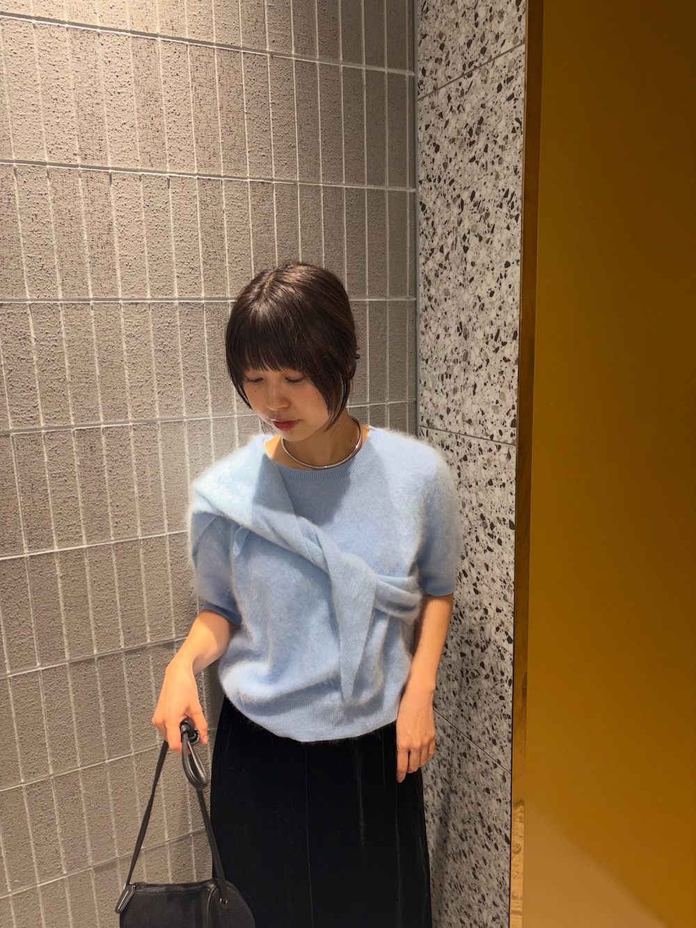 ブルー系のニット/セーター、ブラック系のスカート、ブラック系のショルダーバッグを着用したレディースの秋コーディネートの2枚目の写真
