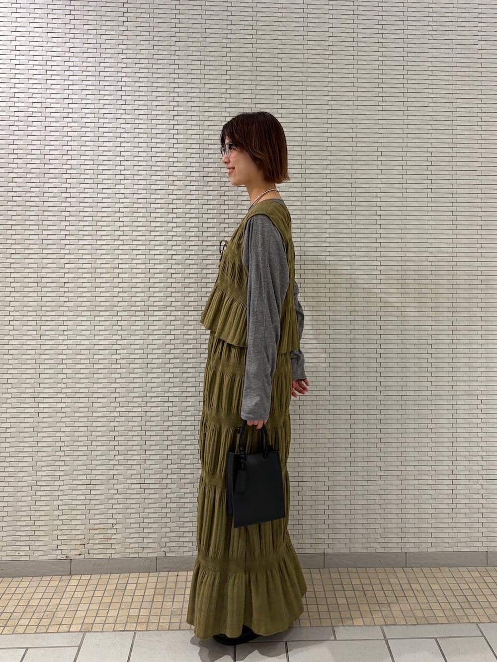 グリーン系のセットアップ、グレー系のTシャツ/カットソー、ブラック系のハンドバッグを着用したレディースの春コーディネートの2枚目の写真