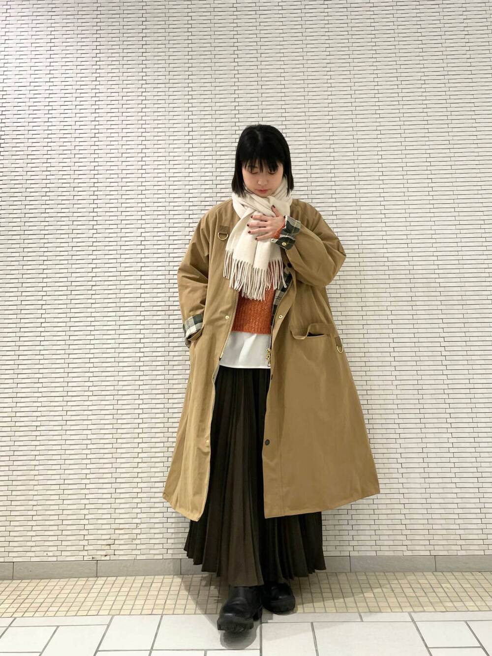 ブラック系のブーツ、ホワイト系のTシャツ/カットソー、オレンジ系のニット/セーターを着用したレディースの冬コーディネートの3枚目の写真