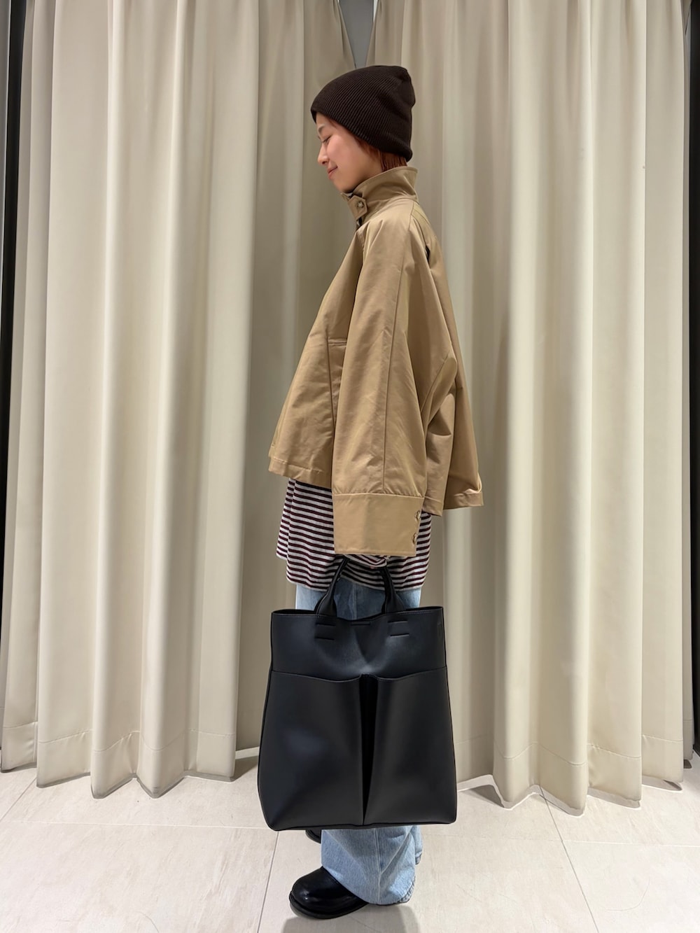 ベージュ系のステンカラーコート、レッド系のニット/セーター、ブラック系のショルダーバッグを着用したレディースの春コーディネートの2枚目の写真