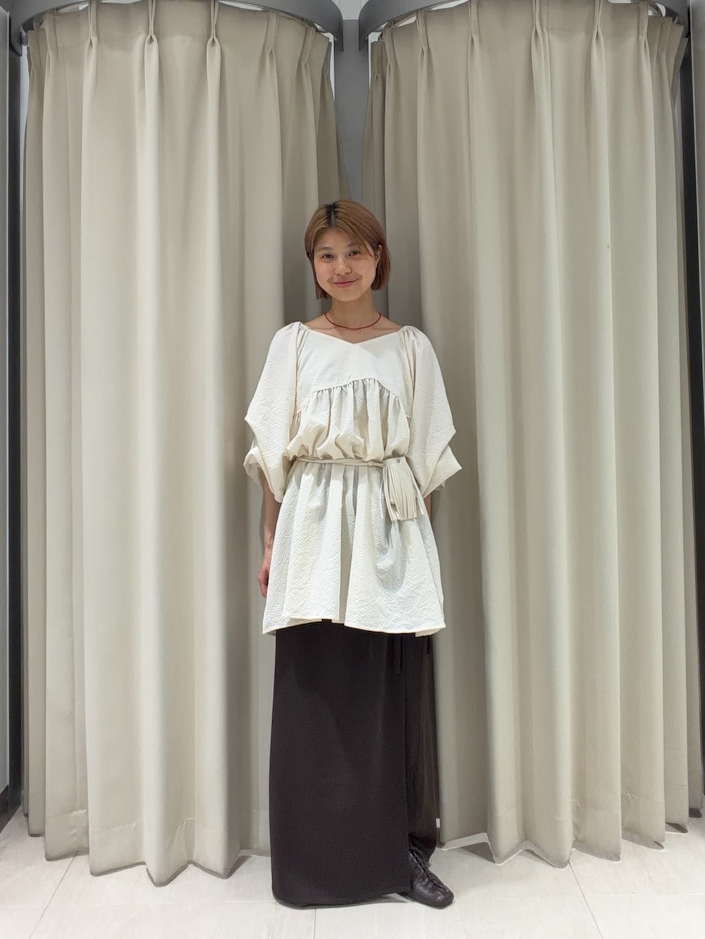 ホワイト系のワンピース、ブラウン系のスカート、ホワイト系のポーチを着用したレディースの夏コーディネートの3枚目の写真