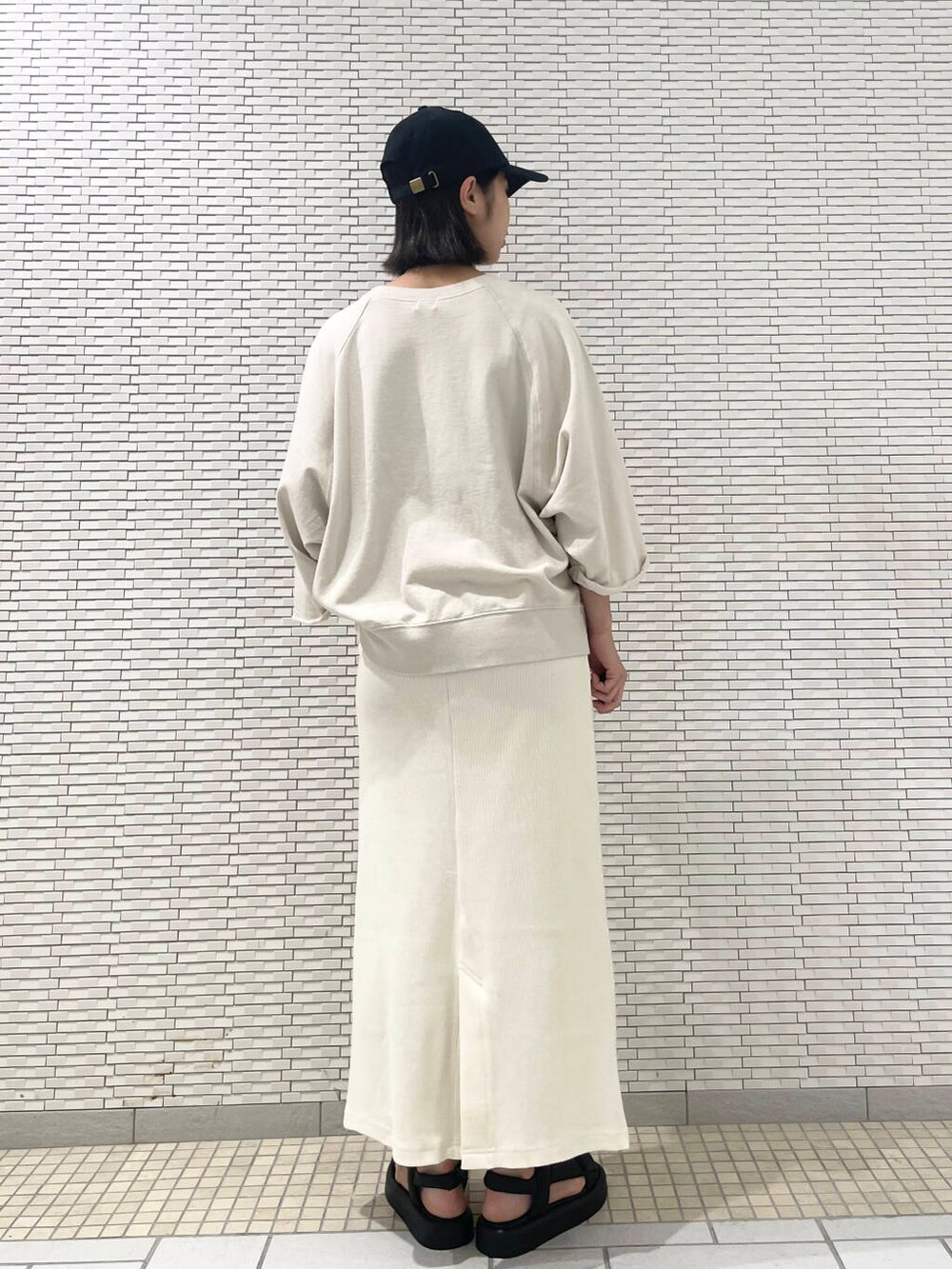 ホワイト系のスカート、ベージュ系のTシャツ/カットソー、ブラック系のキャップを着用したレディースの夏コーディネートの4枚目の写真