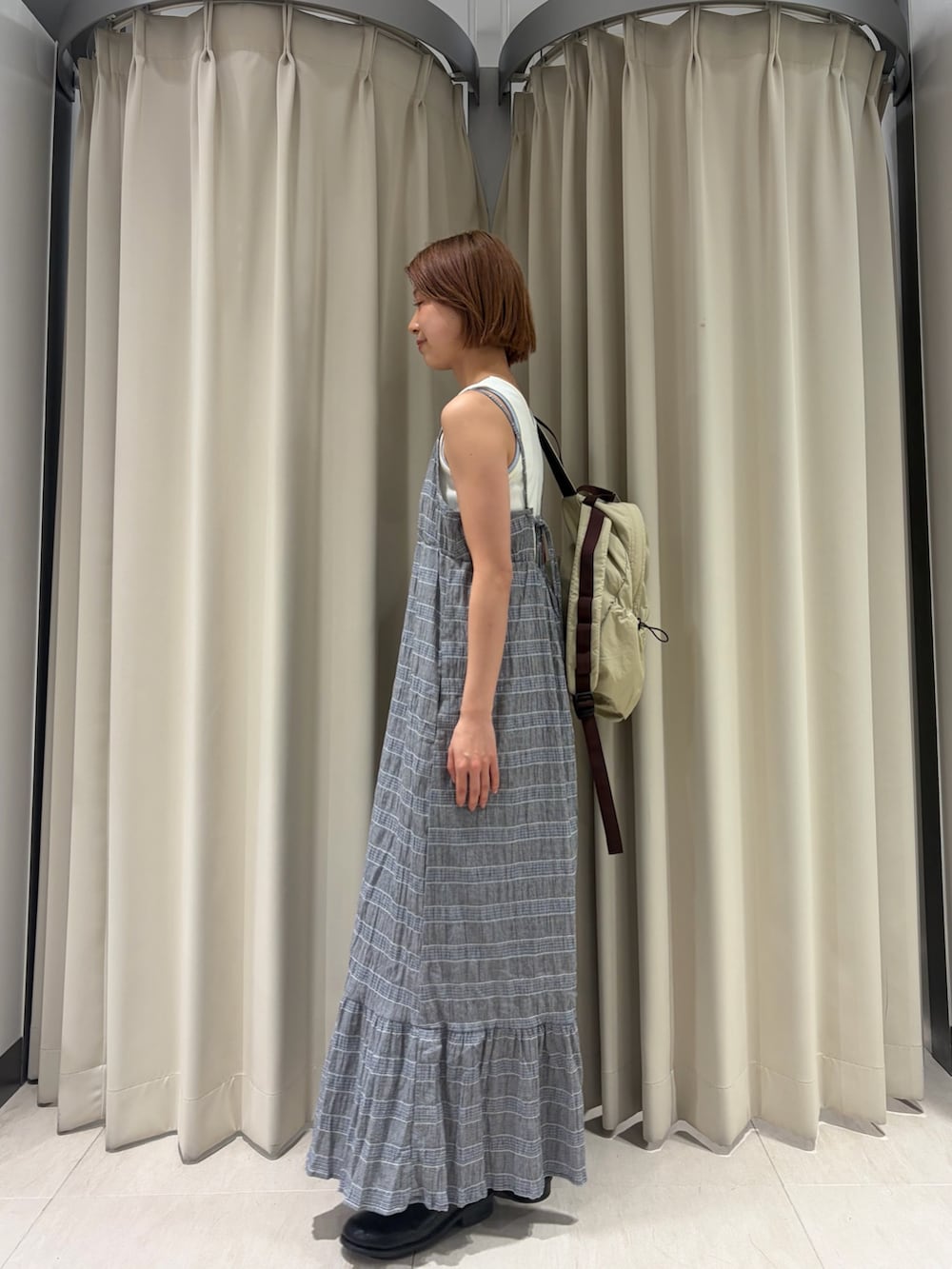 グレー系のワンピース、ホワイト系のタンクトップ、ベージュ系のバックパック/リュックを着用したレディースの春コーディネートの3枚目の写真