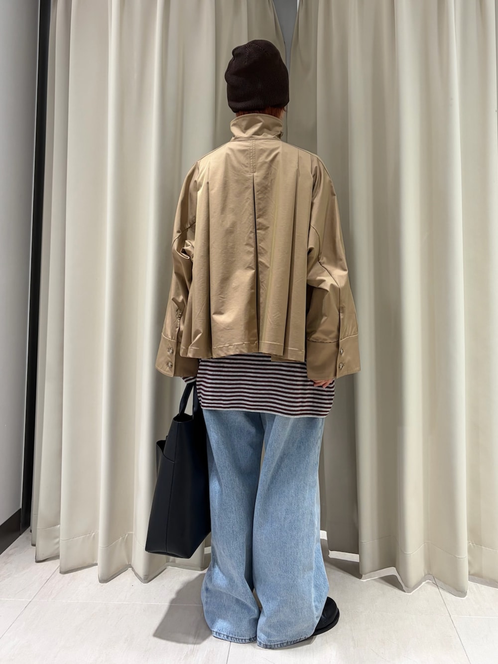 ベージュ系のステンカラーコート、レッド系のニット/セーター、ブラック系のショルダーバッグを着用したレディースの春コーディネートの3枚目の写真