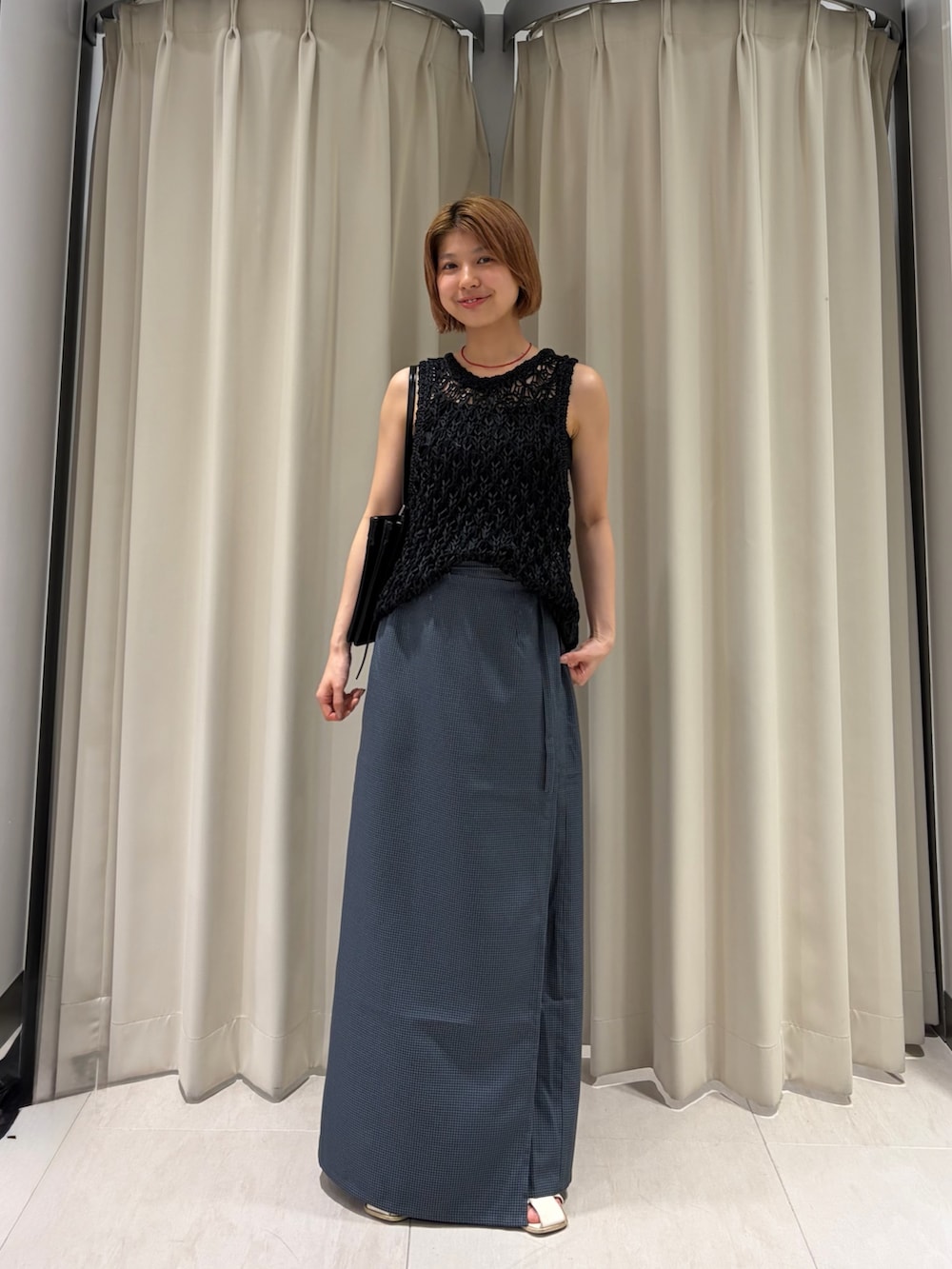 グレー系のスカート、ブラック系のニット/セーター、ブラック系のショルダーバッグを着用したレディースの夏コーディネートの4枚目の写真