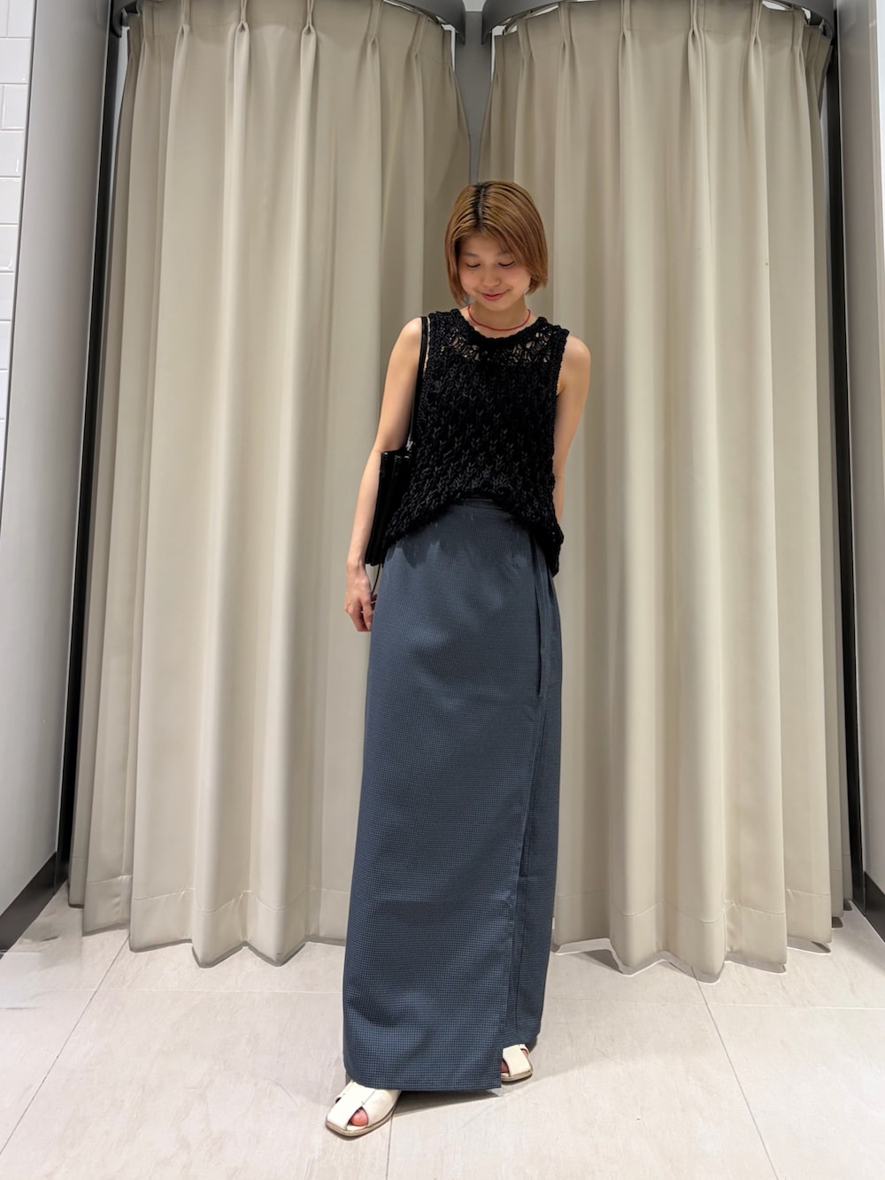 グレー系のスカート、ブラック系のニット/セーター、ブラック系のショルダーバッグを着用したレディースの夏コーディネートの2枚目の写真