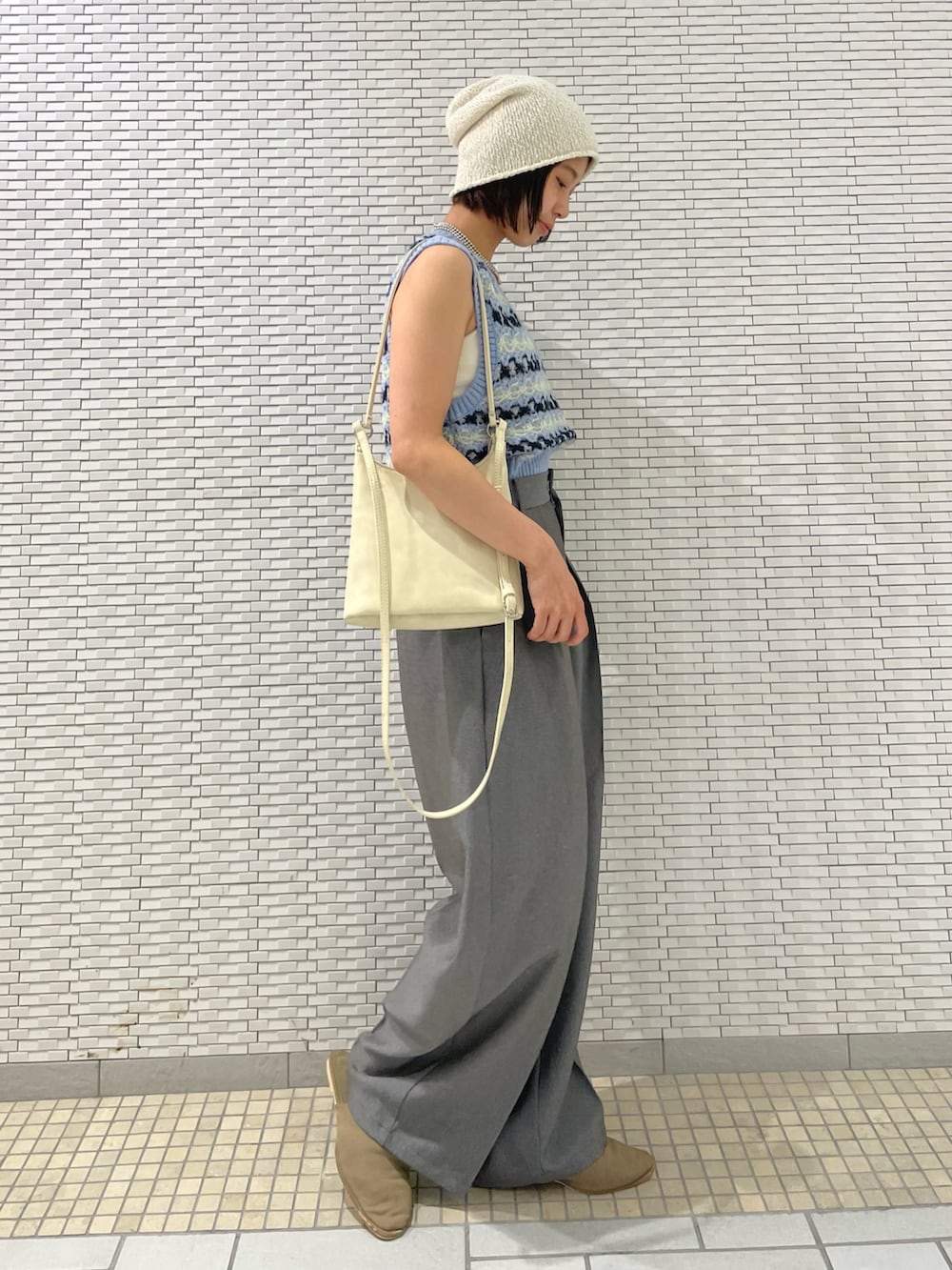 グレー系のその他パンツ、ブルー系のベスト、ホワイト系のショルダーバッグを着用したレディースの夏コーディネートの3枚目の写真