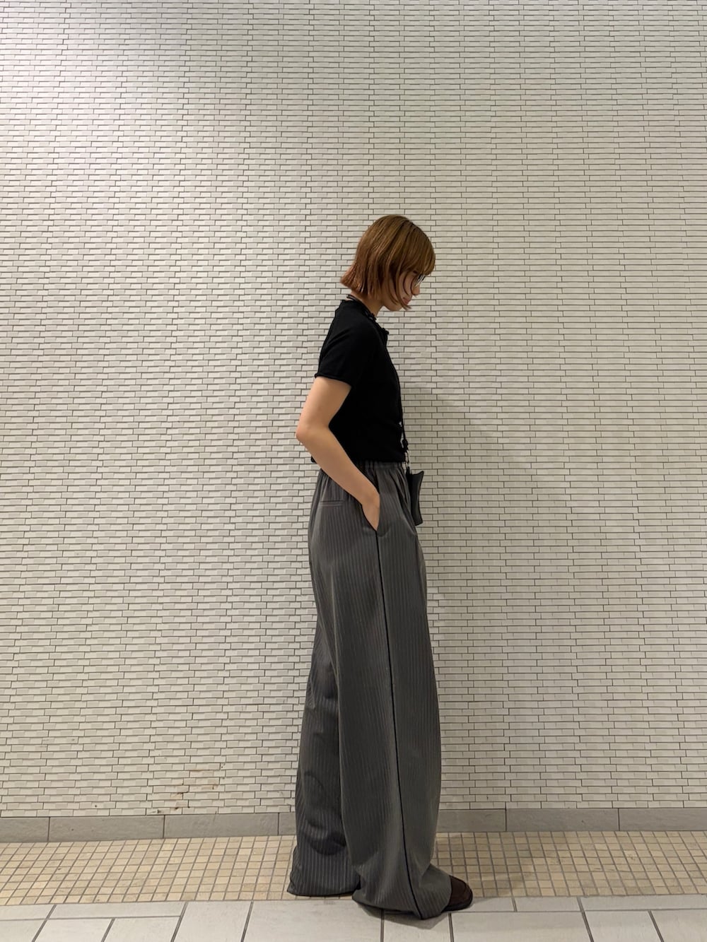 ブラック系のニット/セーター、グレー系のその他パンツ、ブラウン系のローファーを着用したレディースの夏コーディネートの2枚目の写真
