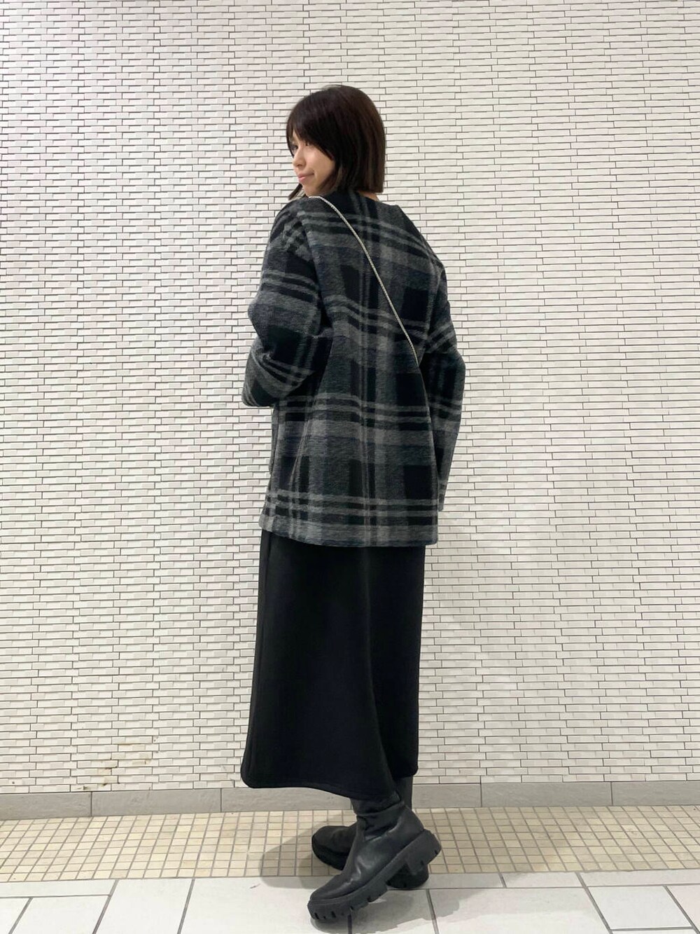 シルバー系のショルダーバッグ、ブラック系のブーツ、グレー系のその他アウターを着用したレディースの秋コーディネートの3枚目の写真