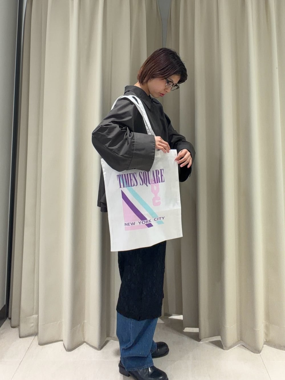 グレー系のステンカラーコート、ブラック系のワンピース、ブルー系のデニムパンツを着用したレディースの春コーディネートの3枚目の写真