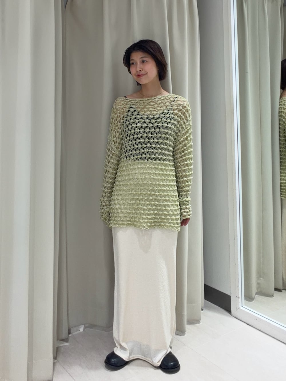 グリーン系のニット/セーター、ホワイト系のスカート、ブラック系のバックパック/リュックを着用したレディースの春コーディネートの3枚目の写真