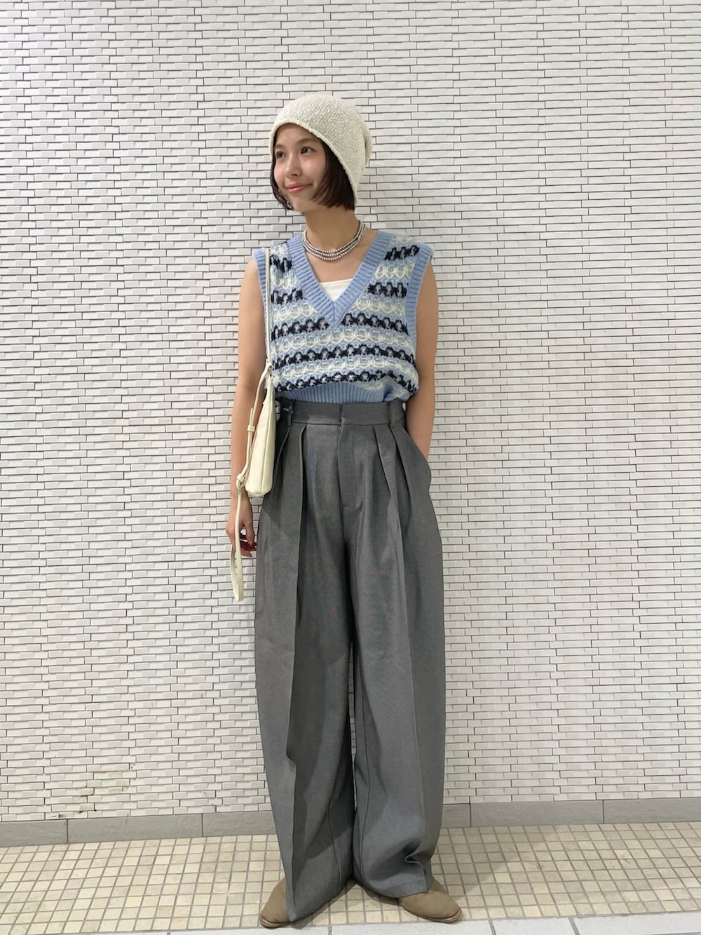 グレー系のその他パンツ、ブルー系のベスト、ホワイト系のショルダーバッグを着用したレディースの夏コーディネートの2枚目の写真