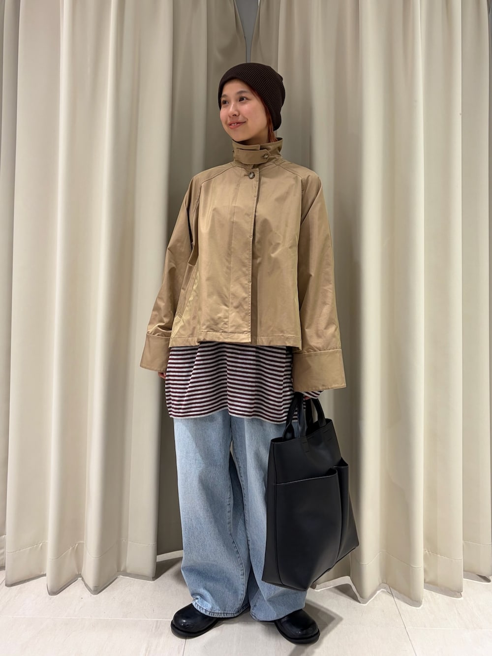 ベージュ系のステンカラーコート、レッド系のニット/セーター、ブラック系のショルダーバッグを着用したレディースの春コーディネートの4枚目の写真