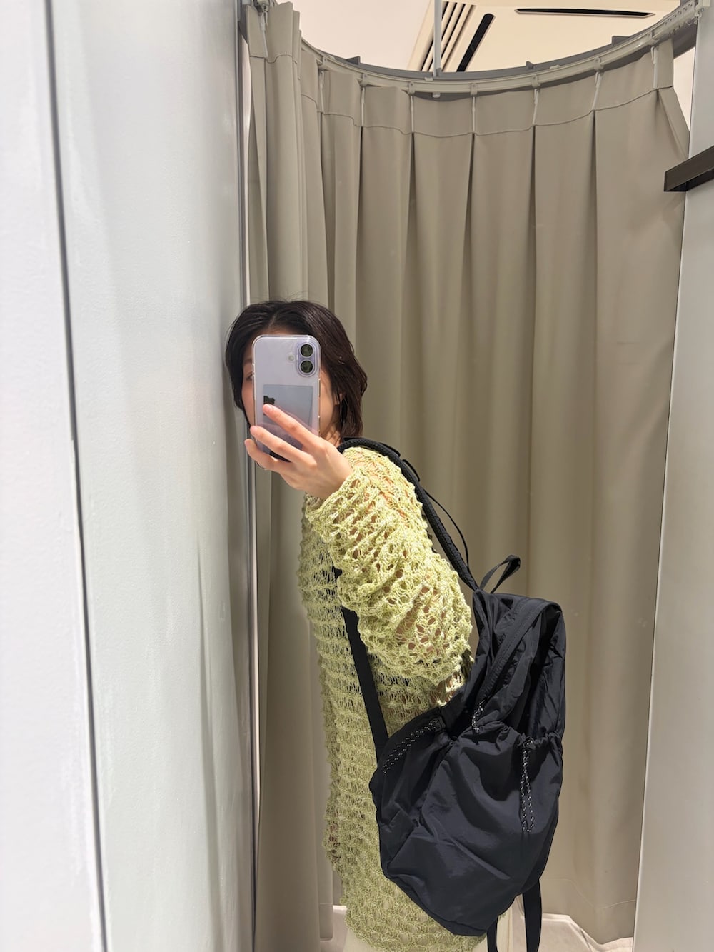 グリーン系のニット/セーター、ホワイト系のスカート、ブラック系のバックパック/リュックを着用したレディースの春コーディネートの2枚目の写真