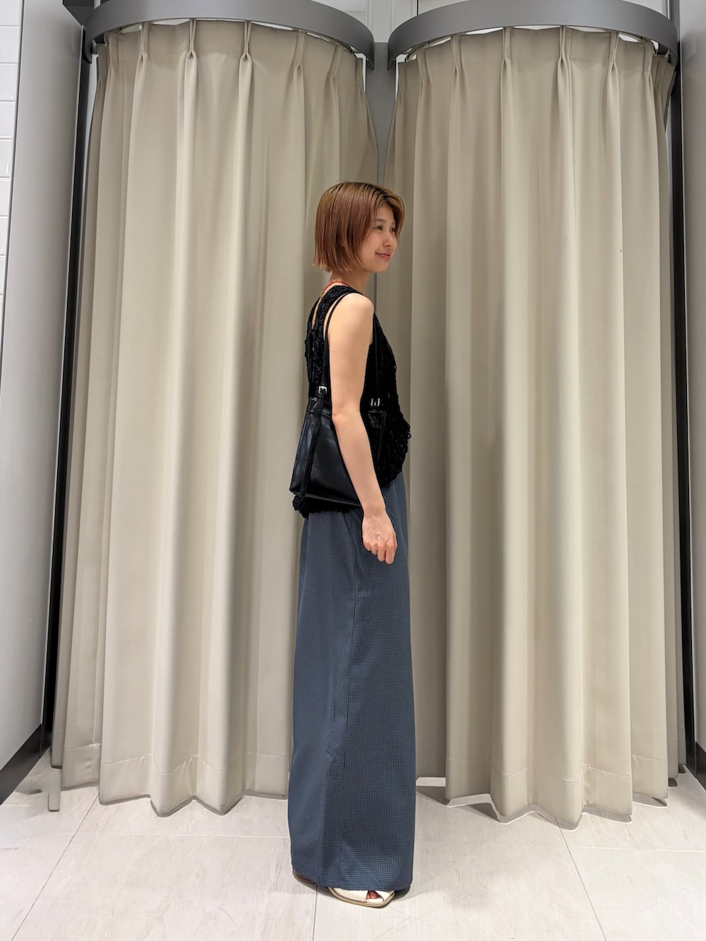 グレー系のスカート、ブラック系のニット/セーター、ブラック系のショルダーバッグを着用したレディースの夏コーディネートの3枚目の写真