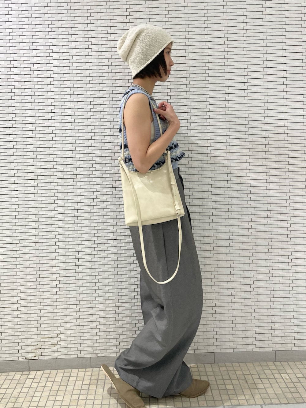 グレー系のその他パンツ、ブルー系のベスト、ホワイト系のショルダーバッグを着用したレディースの夏コーディネートの4枚目の写真