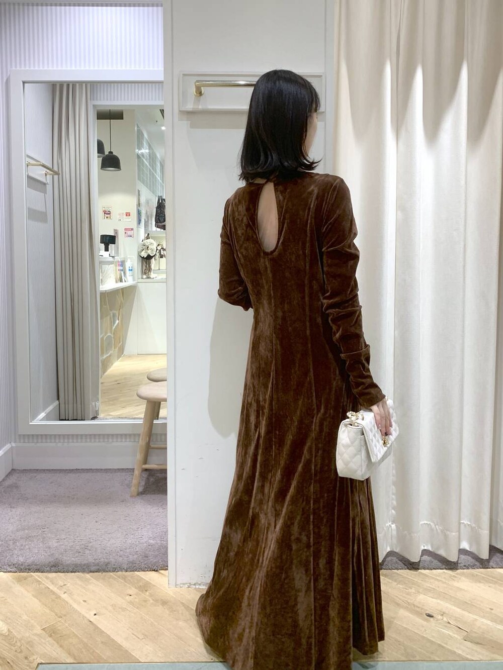 ブラック系のブーツ、ホワイト系のショルダーバッグ、ブラウン系のワンピースを着用したレディースの秋コーディネートの5枚目の写真