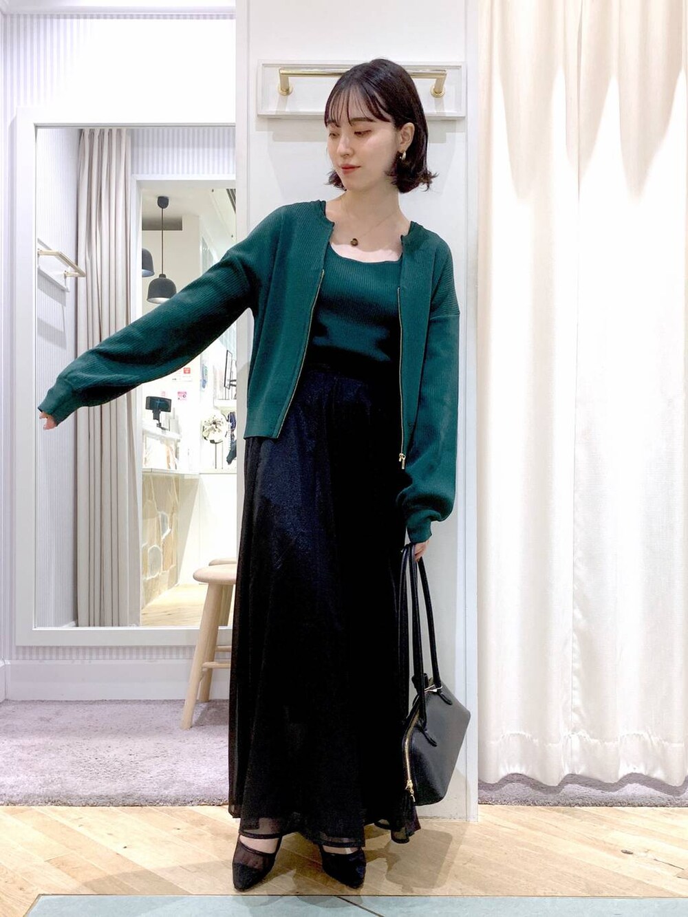 グレー系のスカート、ブラック系のボストンバッグ、グリーン系のカーディガン/ボレロを着用したレディースの夏コーディネートの3枚目の写真