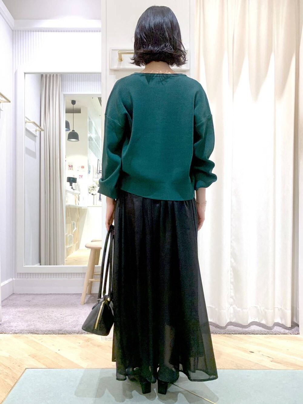 グレー系のスカート、ブラック系のボストンバッグ、グリーン系のカーディガン/ボレロを着用したレディースの夏コーディネートの5枚目の写真