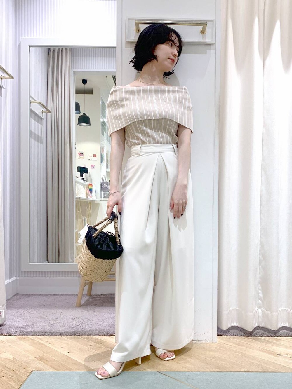 ベージュ系のかごバッグ、ホワイト系のサンダル、ホワイト系のスラックスを着用したレディースの夏コーディネートの5枚目の写真