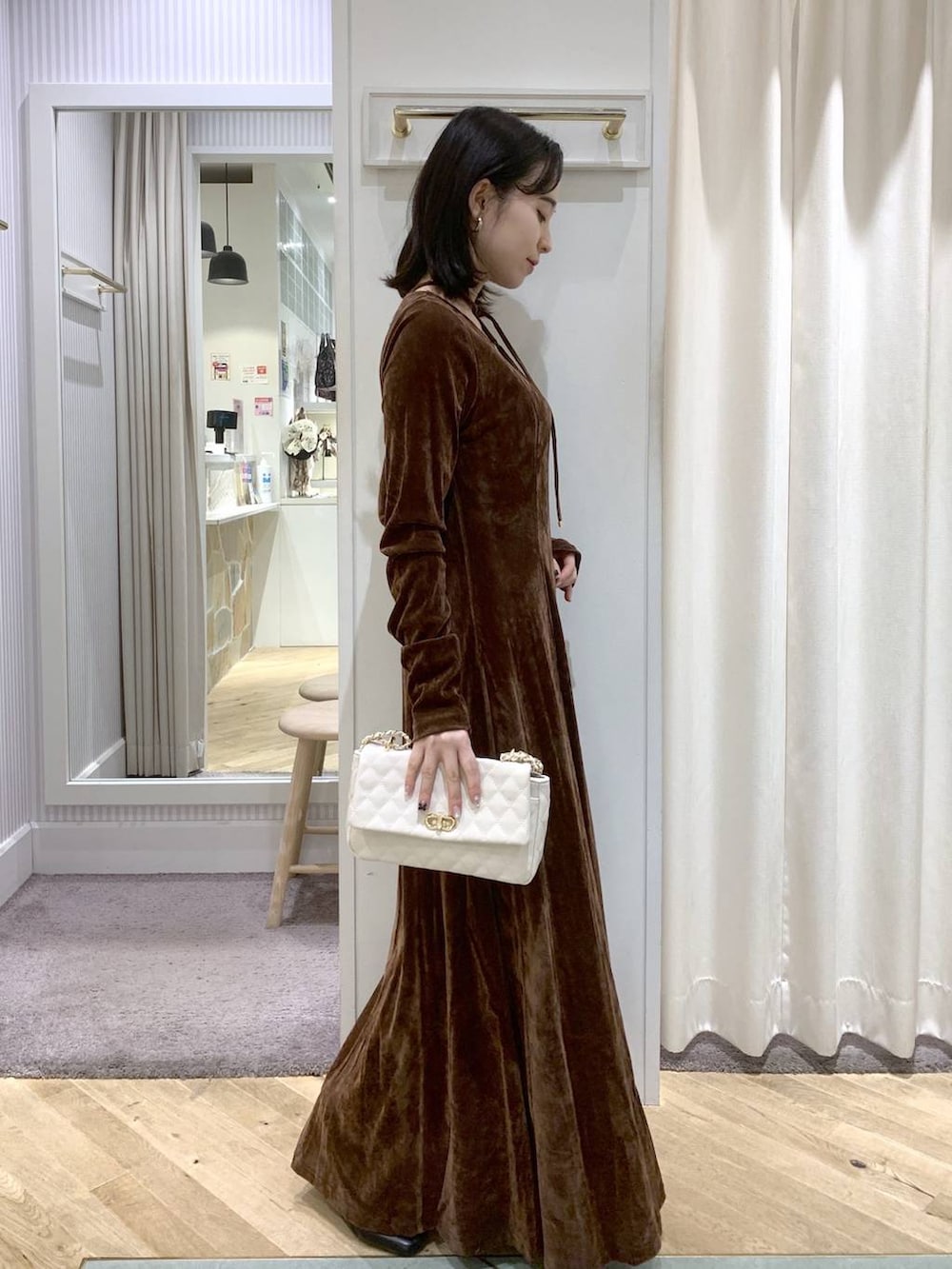 ブラック系のブーツ、ホワイト系のショルダーバッグ、ブラウン系のワンピースを着用したレディースの秋コーディネートの4枚目の写真