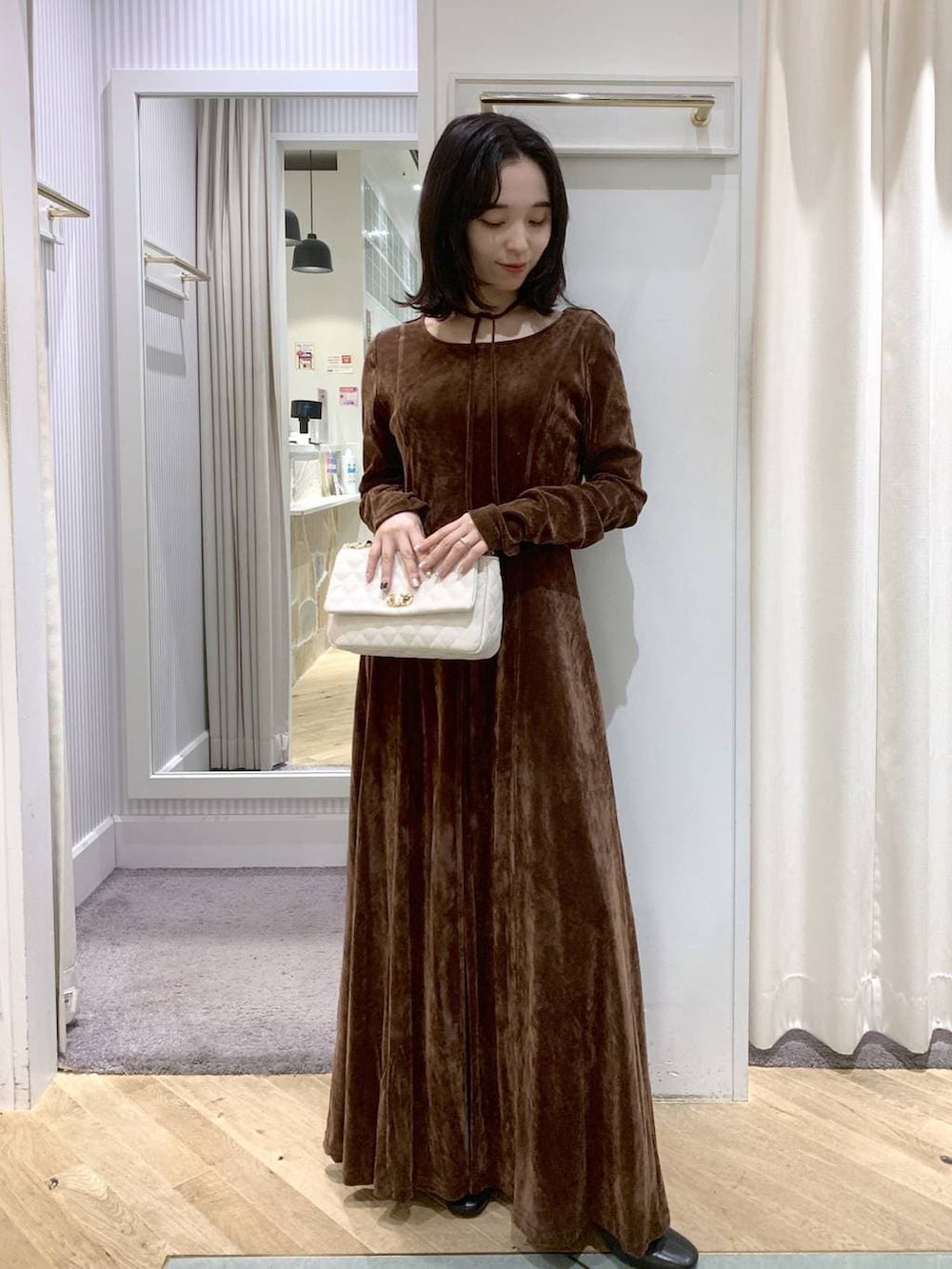 ブラック系のブーツ、ホワイト系のショルダーバッグ、ブラウン系のワンピースを着用したレディースの秋コーディネートの2枚目の写真