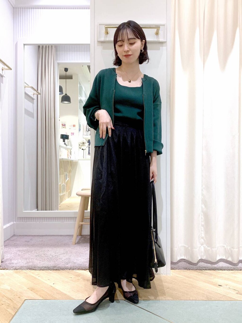 グレー系のスカート、ブラック系のボストンバッグ、グリーン系のカーディガン/ボレロを着用したレディースの夏コーディネートの6枚目の写真