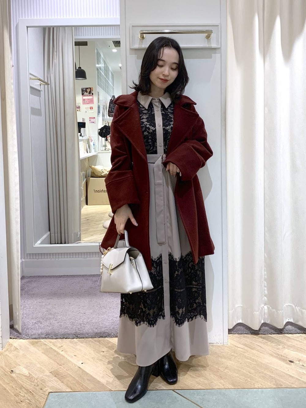 レッド系のピーコート、ブラック系のブーツ、ホワイト系のハンドバッグを着用したレディースの冬コーディネートの2枚目の写真