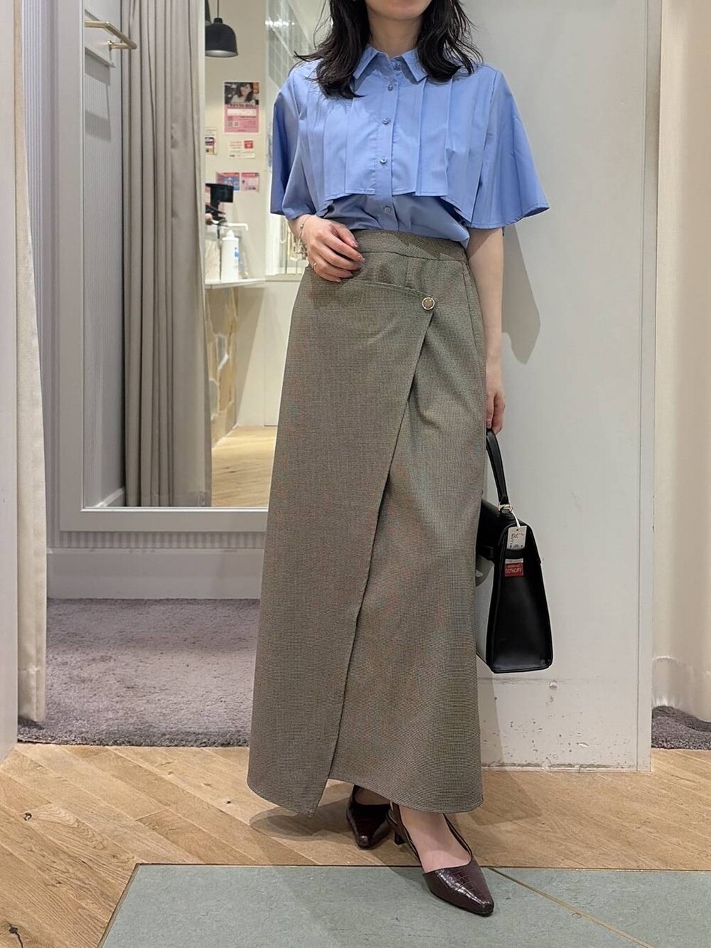 ベージュ系のスカート、ブルー系のシャツ/ブラウス、ブラウン系のパンプスを着用したレディースの夏コーディネートの2枚目の写真
