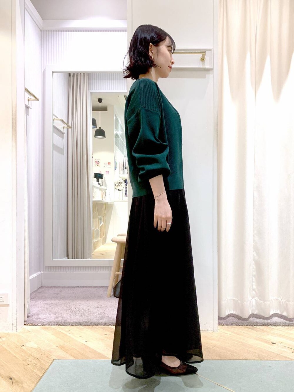 グレー系のスカート、ブラック系のボストンバッグ、グリーン系のカーディガン/ボレロを着用したレディースの夏コーディネートの4枚目の写真