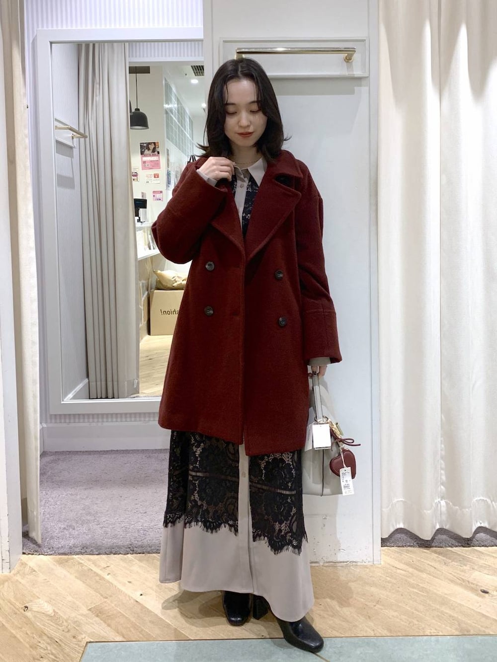 レッド系のピーコート、ブラック系のブーツ、ホワイト系のハンドバッグを着用したレディースの冬コーディネートの8枚目の写真