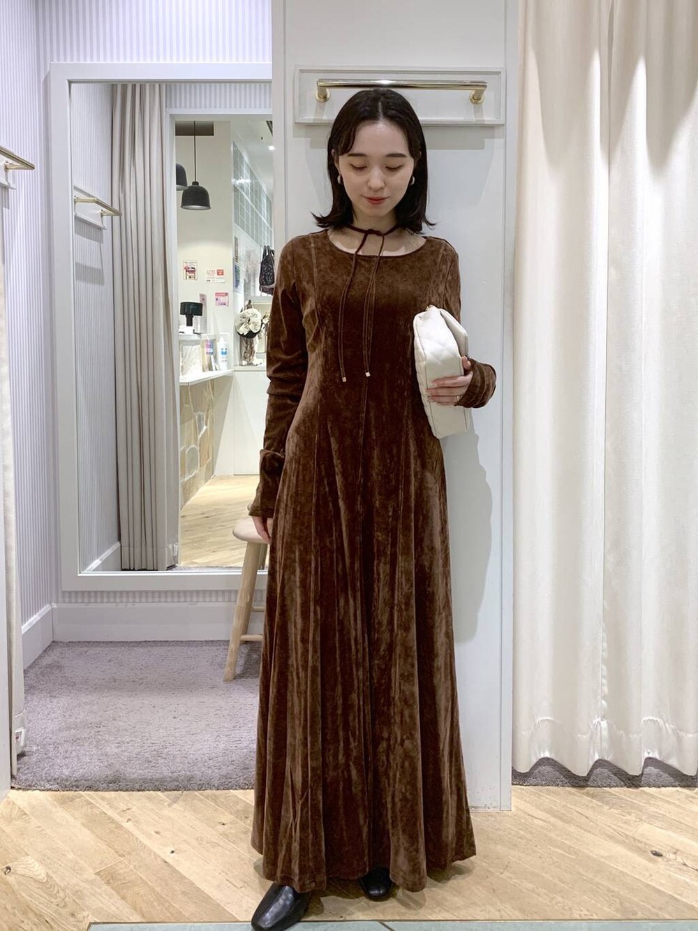 ブラック系のブーツ、ホワイト系のショルダーバッグ、ブラウン系のワンピースを着用したレディースの秋コーディネートの3枚目の写真