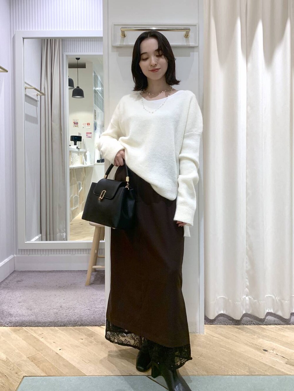 ベージュ系のブルゾン、ブラック系のブーツ、ブラック系のハンドバッグを着用したレディースの秋コーディネートの6枚目の写真